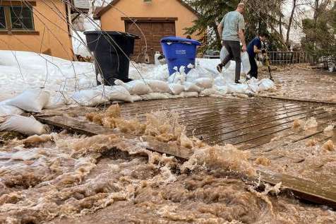 (Trent Nelson | The Salt Lake Tribune) People work to save a home as Emigration Creek rises in Emigration Canyon on Wednesday, April 12, 2023.