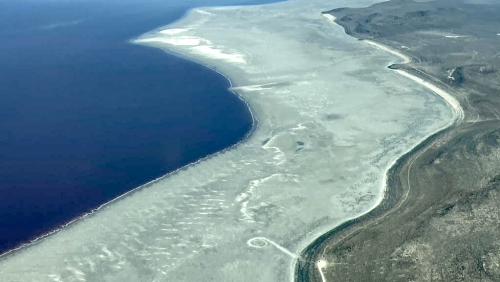 The shore of Great Salt Lake (left) is pictured alongside its historic shoreline (right). The Spiral Jetty lies between them on the dry and dusty lakebed. (Photo courtesy of Bryn Watkins)