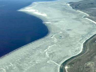  The shore of Great Salt Lake (left) is pictured alongside its historic shoreline (right). The Spiral Jetty lies between them on the dry and dusty lakebed. (Photo courtesy of Bryn Watkins)
