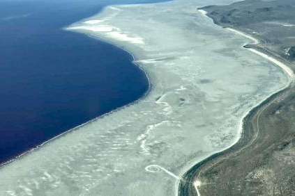  The shore of Great Salt Lake (left) is pictured alongside its historic shoreline (right). The Spiral Jetty lies between them on the dry and dusty lakebed. (Photo courtesy of Bryn Watkins)