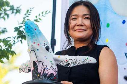 Salt Lake-based artist Jiyoun Lee-Lodge holds up a model of her mural "Open Your Eyes" during an unveiling of the new mural for "Out of the Blue" in Salt Lake City on Saturday. The mural will be painted on the city's whale sculpture in the coming weeks. (Carter Williams, KSL)