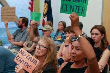 Lorena Bush holds a NO DATA CENTER sign during a public hearing in Salt Lake City on Monday. Opponents are concerned a permit would authorize the discharge of up to 260,000 gallons per day of concentrated industrial brine. (Kristin Murphy, Deseret News)