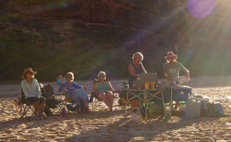 Group of women rafters cooking and relaxing on the bank of the river. (Photo courtesy Zan Merrill).