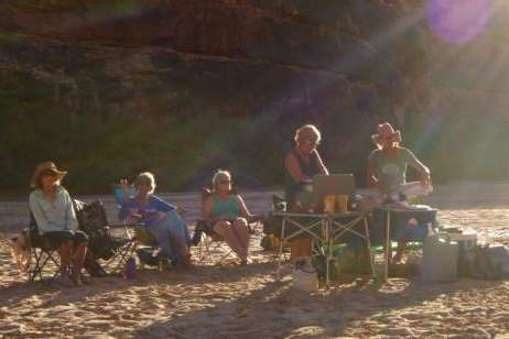 Group of women rafters cooking and relaxing on the bank of the river. (Photo courtesy Zan Merrill).