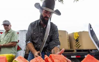 Watermelon juice flies off his machete while Weston Vetere, from Kanab, chops watermelons to give away at the Vetere stall during the 118th annual Melon Days Festival in Green River on Saturday, Sept. 21, 2024. | Brice Tucker, Deseret News