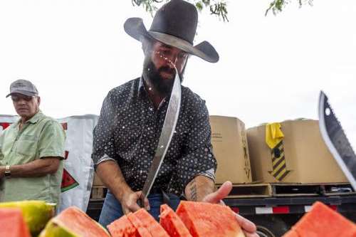 Watermelon juice flies off his machete while Weston Vetere, from Kanab, chops watermelons to give away at the Vetere stall during the 118th annual Melon Days Festival in Green River on Saturday, Sept. 21, 2024. | Brice Tucker, Deseret News