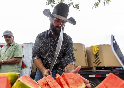 Watermelon juice flies off his machete while Weston Vetere, from Kanab, chops watermelons to give away at the Vetere stall during the 118th annual Melon Days Festival in Green River on Saturday, Sept. 21, 2024. | Brice Tucker, Deseret News