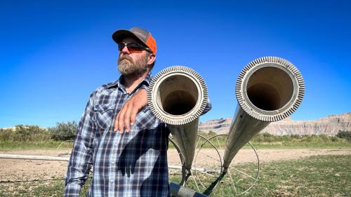 Farmer and rancher Coby Hunt stands next to idle irrigation equipment in one of his fields near the town of Green River, Aug. 19, 2024. Utah is launching a new program that will pay producers to leave their fields empty, as Hunt has done, and leave their irrigation water in the Colorado River system. (David Condos/KUER)