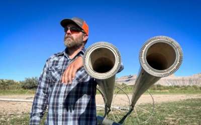 Farmer and rancher Coby Hunt stands next to idle irrigation equipment in one of his fields near the town of Green River, Aug. 19, 2024. Utah is launching a new program that will pay producers to leave their fields empty, as Hunt has done, and leave their irrigation water in the Colorado River system. (David Condos/KUER)